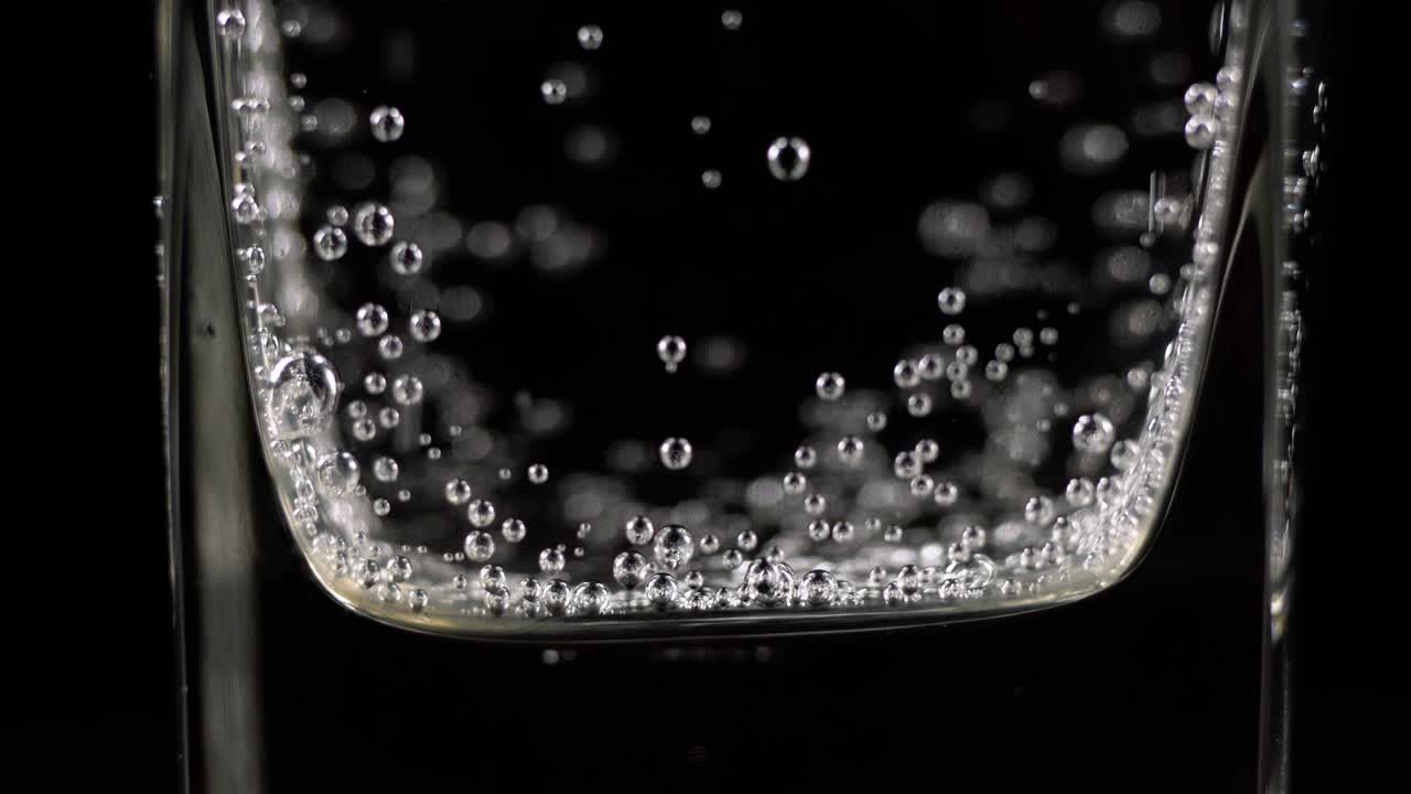 유리잔에 미네랄 워터 거품의 근접. 어두운 배경에 산소 공을 가진 탄산 신선한 스파클링 음료의 매크로 상점