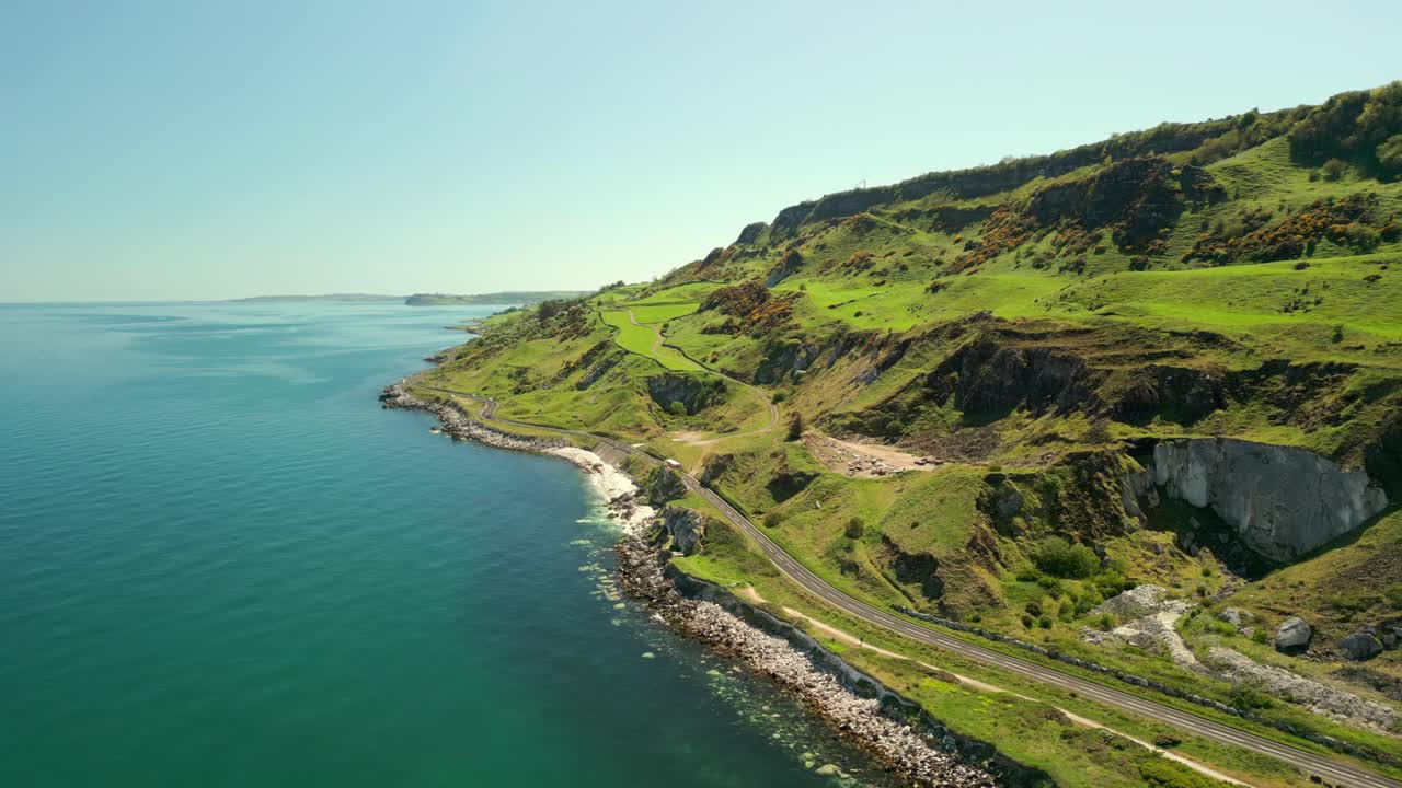 Reversing, travelling aerial video of the Causeway Coastal Route in County Antrim, Northern Ireland, UK, on a bright and sunny day. Filmed in 4K, 60FPS and with Rec709 color.