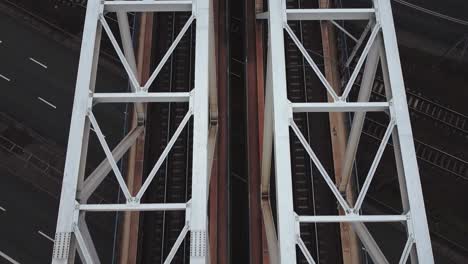 Cinematic-drone-video-of-train-tracks-on-a-bridge-above-car-road