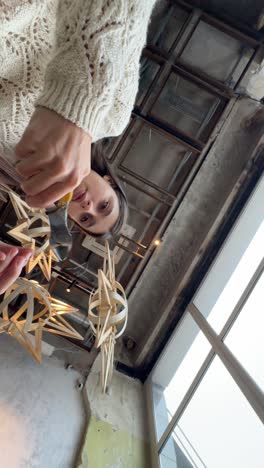 woman wearing a knitted sweater interacting with wooden star decorations in a cafe.