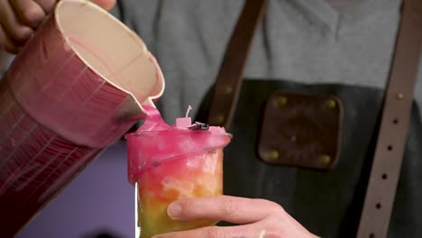 verter cera rosa caliente en una forma para obtener velas hechas a mano