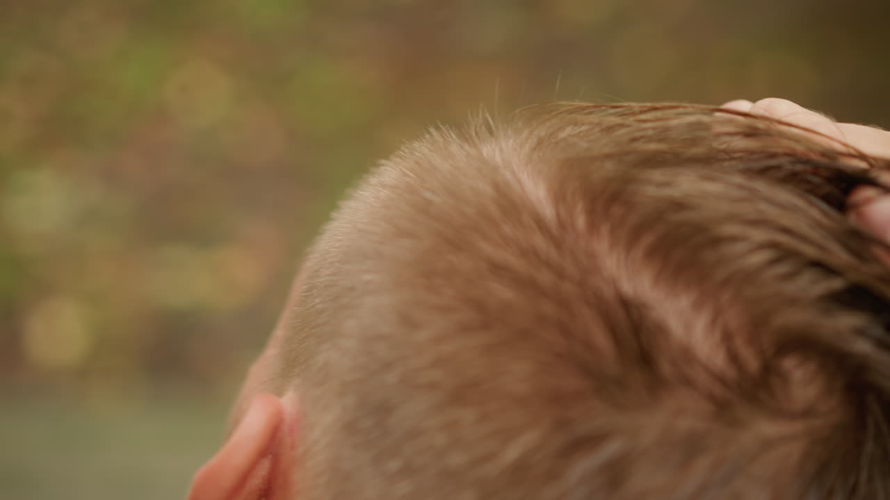 Relaxed grooming following workout session, Casual grooming after exercise with raindrops on hair, Informal hairstyle touchup following physical activity under rainy weather conditions