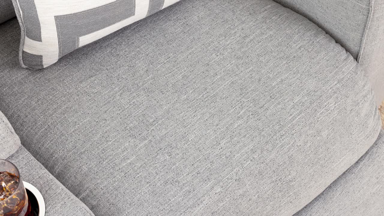 Camera zooms into grey cushion and decor atop upholstered seat