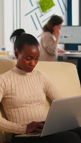 vertical video concentrated african business woman answering emails typing on laptop