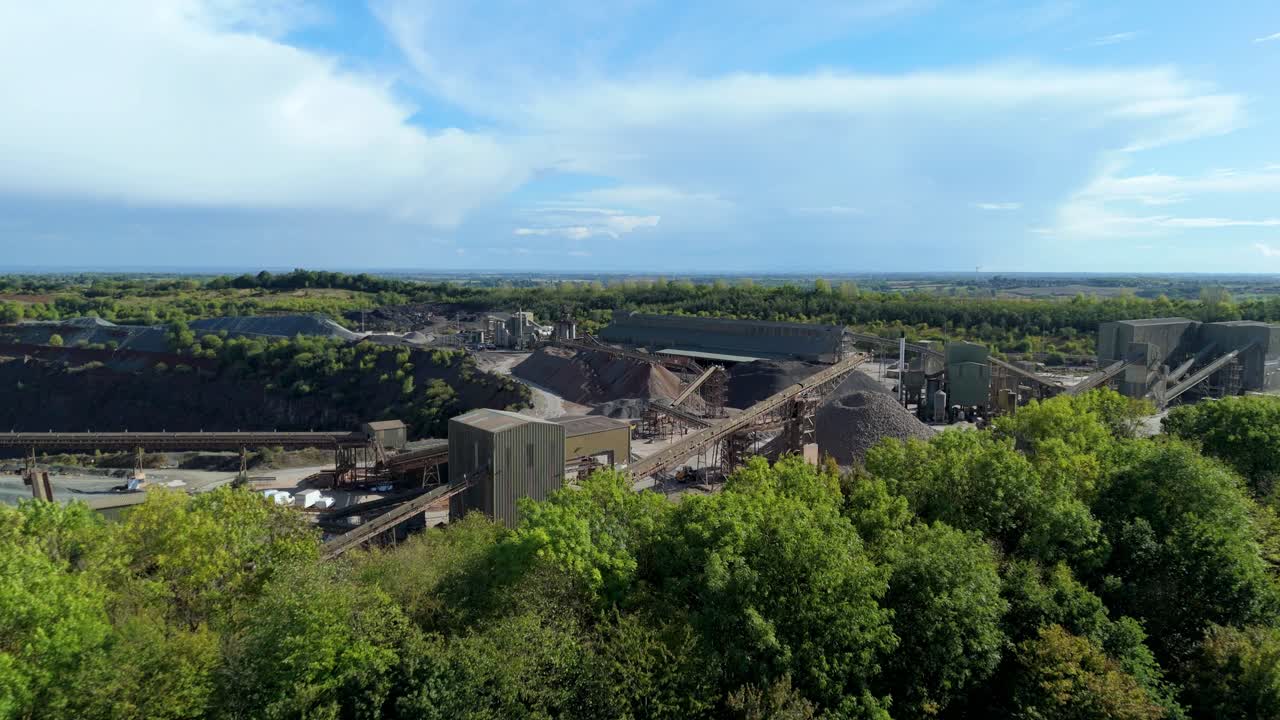 - Elevated drone view of large aggregates site in Coalville UK with visible excavation layers and industrial layout