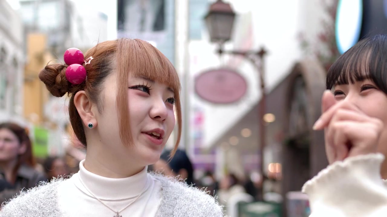 賑やかな都会の商店街で、おしゃれな2人の若い女性が屋外で話したり笑ったりしています。