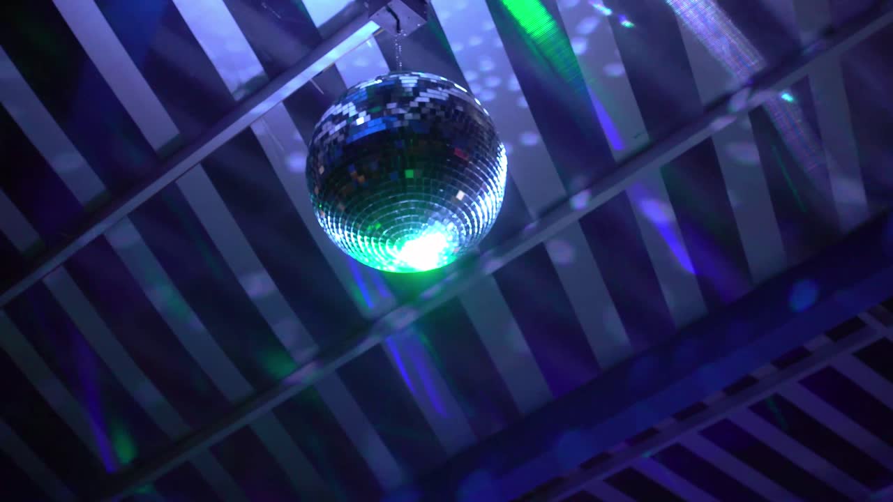Bola de discoteca luminosa refleja luces de colores.