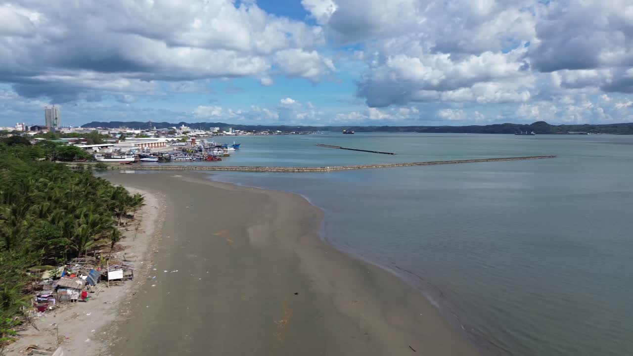 Vista aerea di una spiaggia appartata a Iloilo City, Filippine, con piccole case sparse lungo la costa tropicale. Tranquillo paesaggio costiero sull'isola di Panay con sviluppo minimo e acque blu