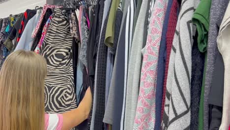 young woman in casual clothes chooses elegant blouse in store