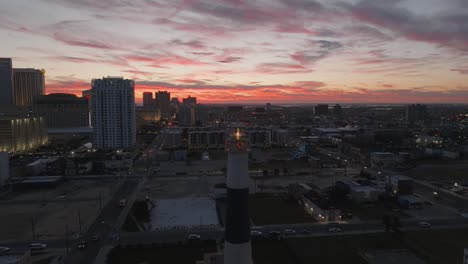 Rising-above-a-lighthouse-in-Atlantic-City,-NJ-with-the-skyline-and-sunset-in-the-background