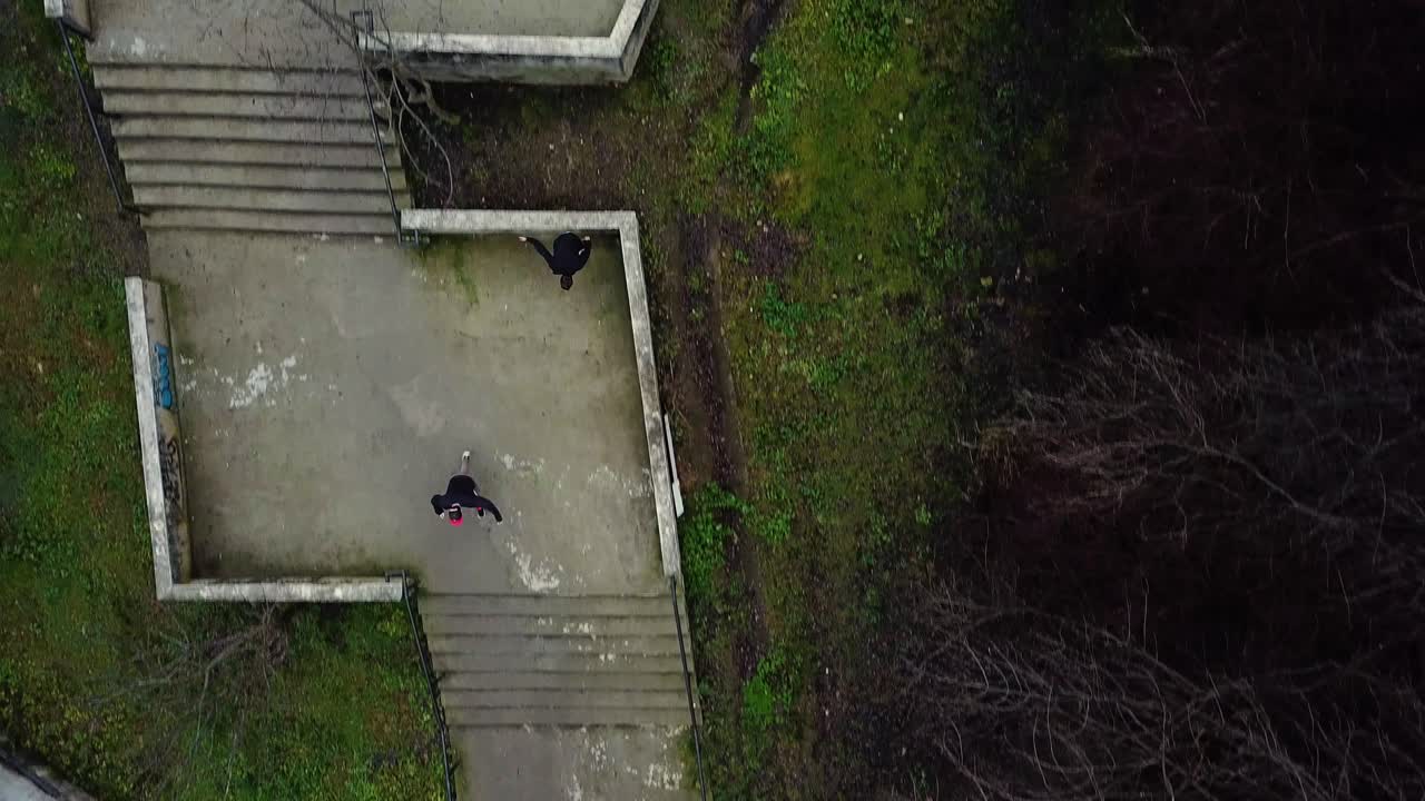 toma aérea directa de drones de dos corredores libres de parkour que bajan escaleras