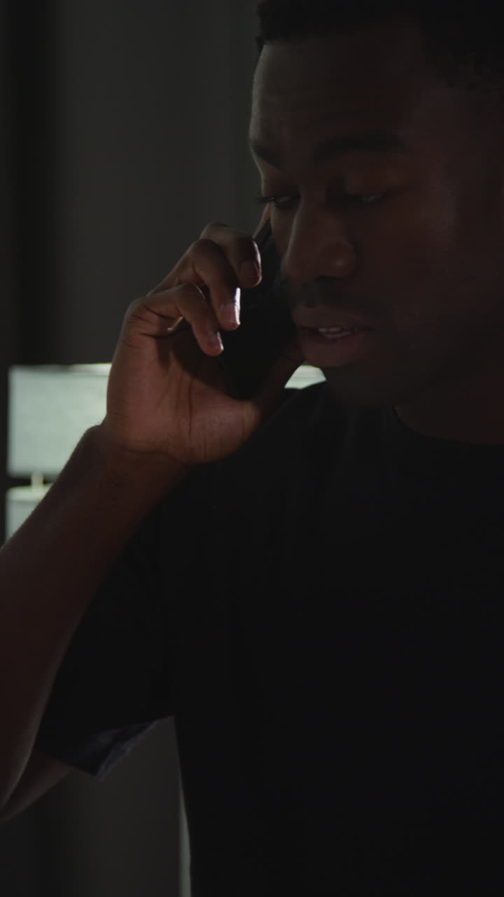 집에서 드폰으로 대화하는 젊은 남자의 수직 클로즈업 비디오. 나쁜 소식을 듣고 화를 내며 반응하는 모습.