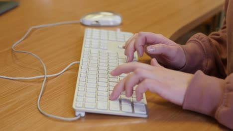 closeup of hands type on keyboard on a desk