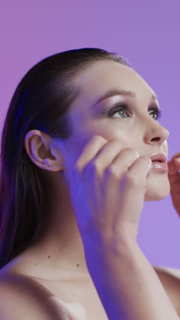 vertical video of caucasian woman with brown hair and make up touching face, copy space, slow motion