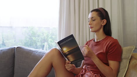 relaxing on sofa, woman reading book and enjoying coffee at home
