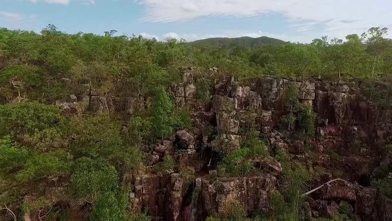 Falesia di quarzite si erge sopra la densa boscaglia del Cerrado ad Almecegas, con pareti rocciose erose, vegetazione autoctona e altipiani ondulati vicino ad Alto Paraiso de Goias, ascesa di drone