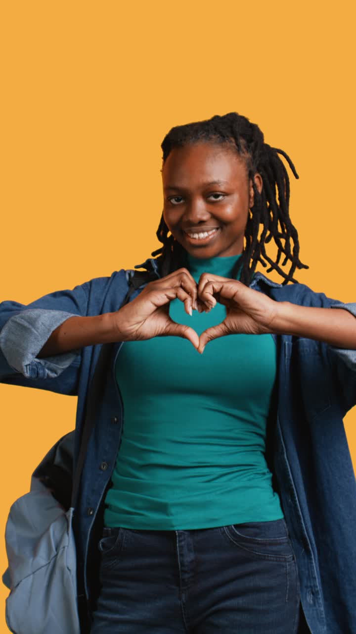 Giovane donna afroamericana che fa un gesto a cuore e sorride