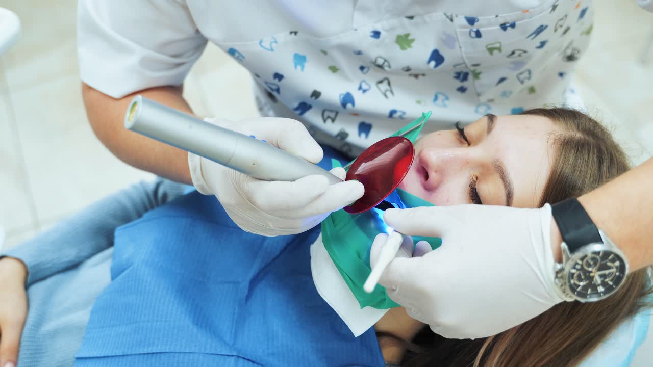 The girl in the office at the dentist. Dental restoration and material polymerization with UV light