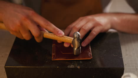 Handwerker-Klopft-Mit-Hammer-Am-Tisch-Auf-Lederwerkstück