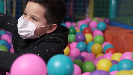 happy 5 year old boy with mask in a ball pool throwing balls to camera. Slow motion