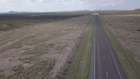 drone — highway in west texas with mountains in background and car driving through