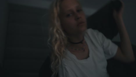 portrait of a blonde girl in a white t-shirt who sharply falls her head in bed and covers herself with a blanket at night