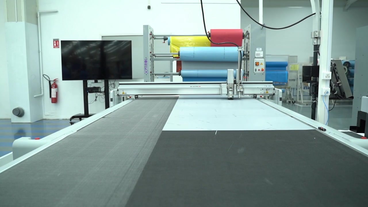 Uma grande mesa de corte de tecido automatizada em uma oficina industrial limpa.