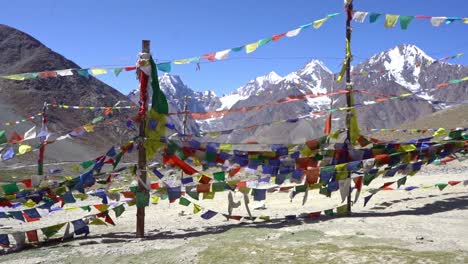 buddhist prayer flags blow by the wind with mountains in background - wide shot