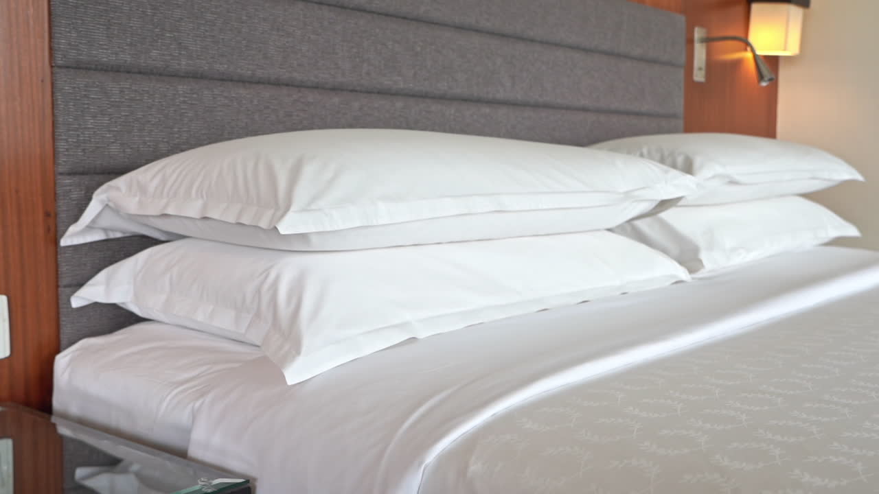 almohadas dobles en una cama cómoda con sábanas blancas en la habitación del hotel