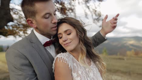 Lovely-young-newlyweds-bride-and-groom-embracing,-hugging-on-mountain-slope,-wedding-couple-in-love