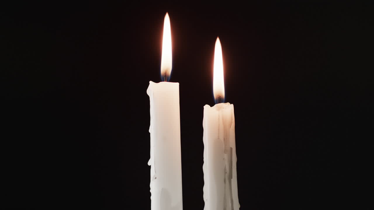 Video di due candele bianche con fiamma bianca e spazio per il testo su sfondo nero