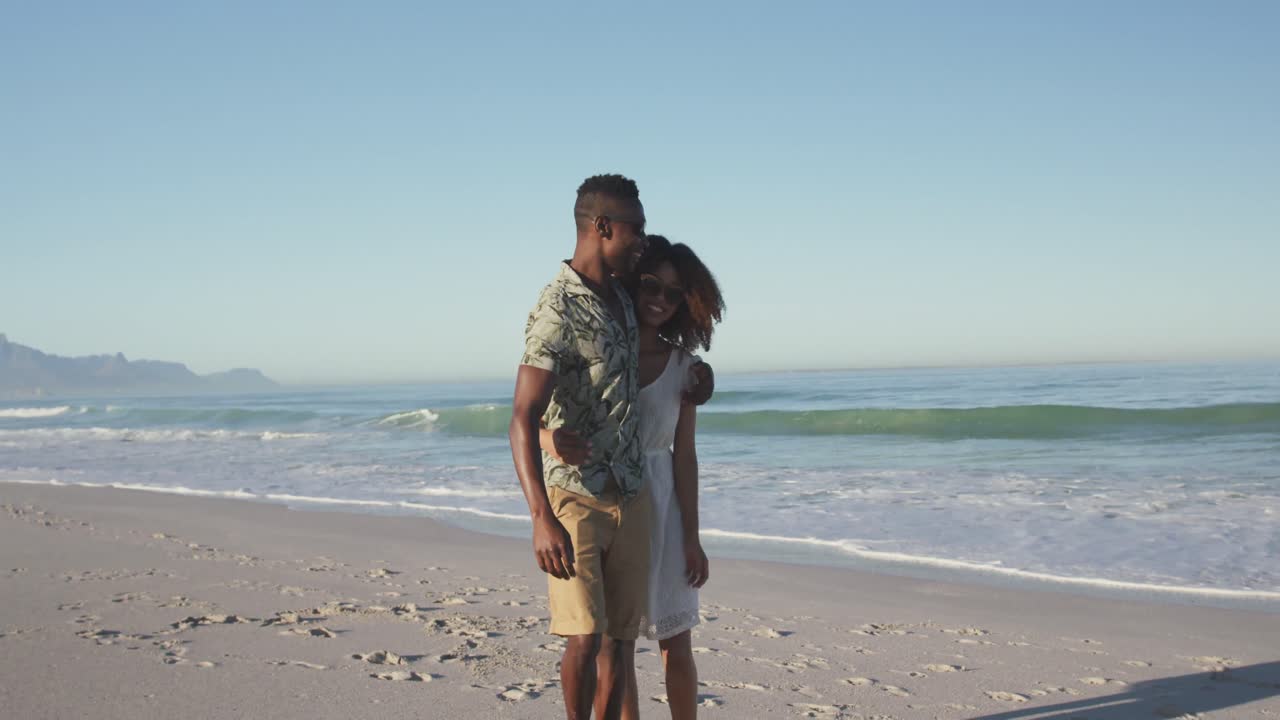 African American couple walking side by side at beach