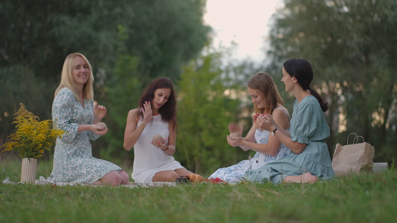 A group of young girls in the open air conduct a master class in clay modeling. Joint activity communication laughter common hobby women's circle creative activities.