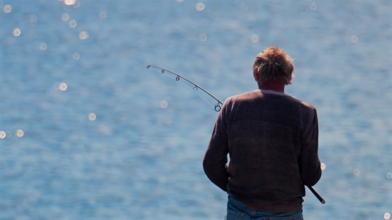 View of an old man fishing in the sea on a sunny day