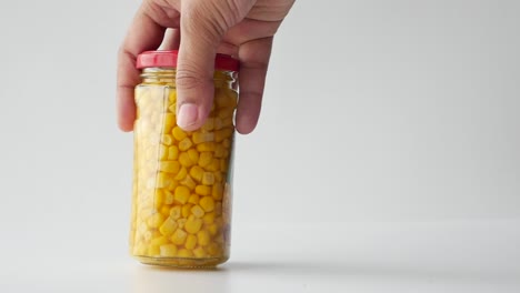 hand holding a jar of canned corn