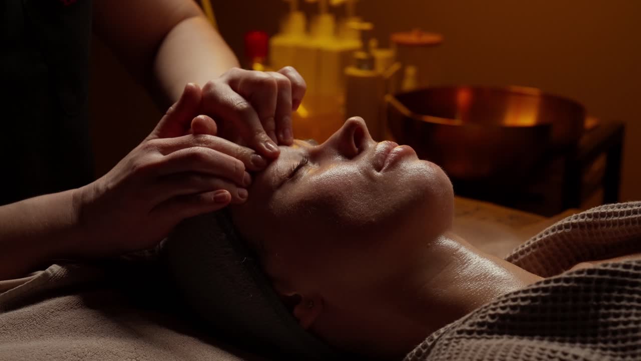 Kvinde får afslappende ansigtsmassage i et dæmpet oplyst spa