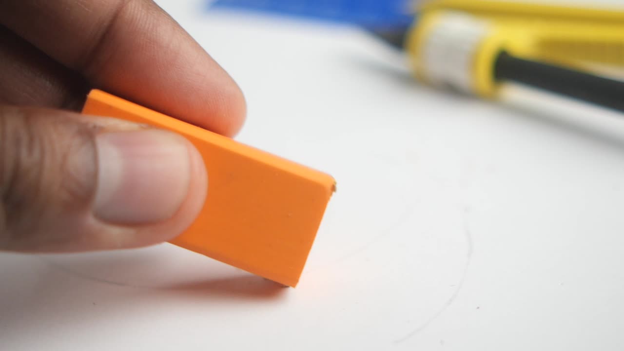 Hand holding an orange rectangular eraser