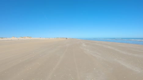 POV-driving-on-wide-beach-of-a-barrier-island-on-the-Gulf-of-Mexico-at-low-tide-with-sand-dunes-off-to-the-right---Texas