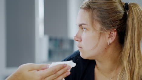 blonde caucasian woman in the process of labor. male hand using napkin to clean female face. close up.