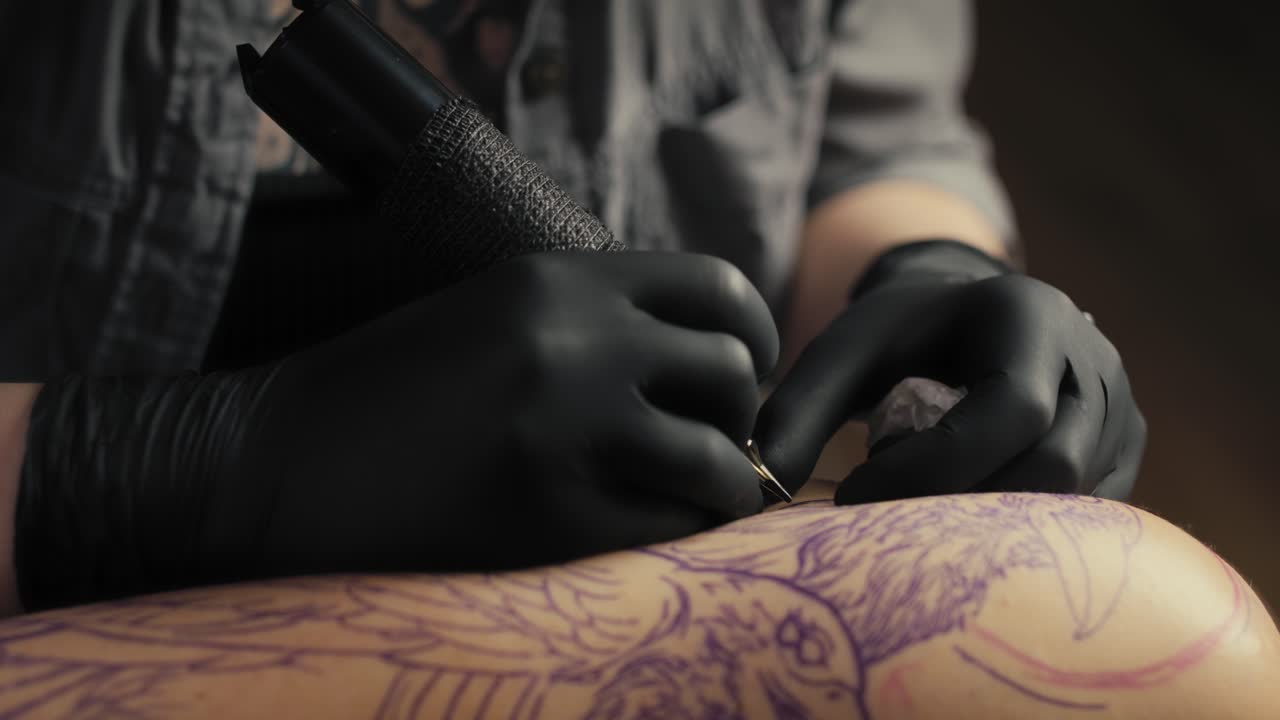 Primo piano di un tatuatore che disegna sul braccio di un cliente.