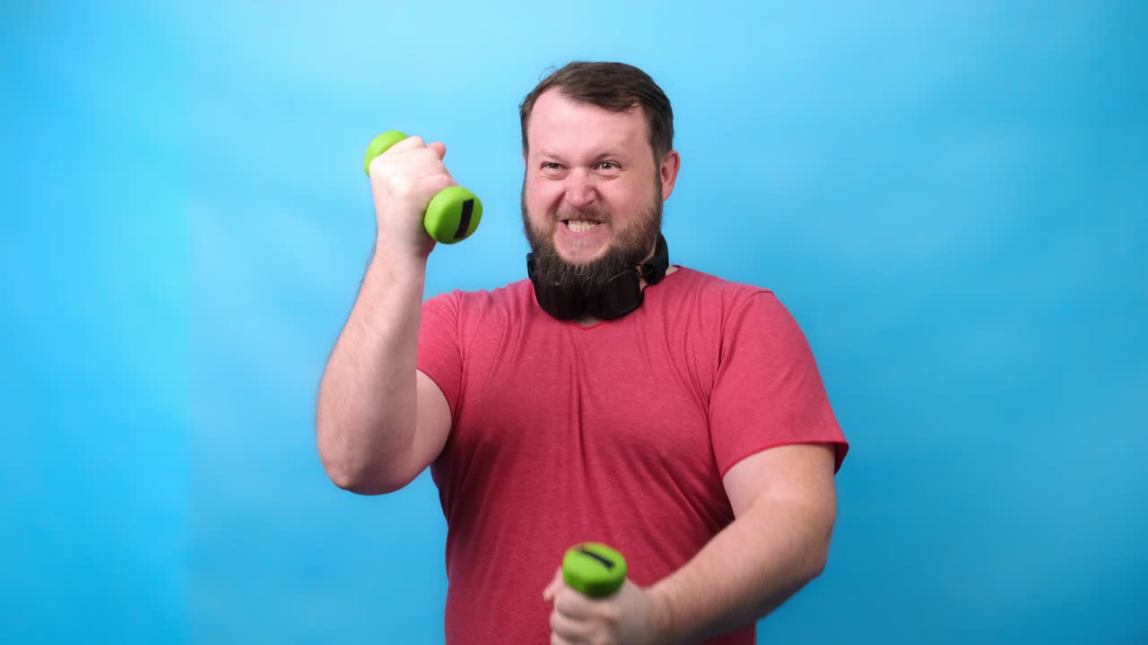 bonito culturista de barba gruesa en camiseta rosa con pesas muy pequeñas está muy tenso haciendo ejercicios