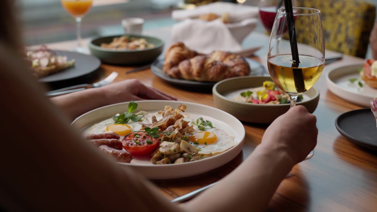 Leisurely brunch moment at a modern restaurant hands reaching for elegant breakfast dishes and
