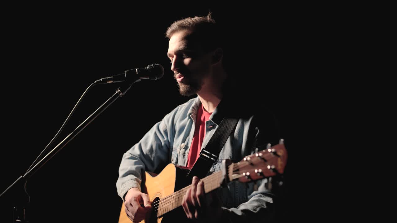 un músico está tocando la guitarra en un gran escenario con miembros de la audiencia sosteniendo linternas en el fondo. el auditorio está lleno de hermosas luces parpadeantes.