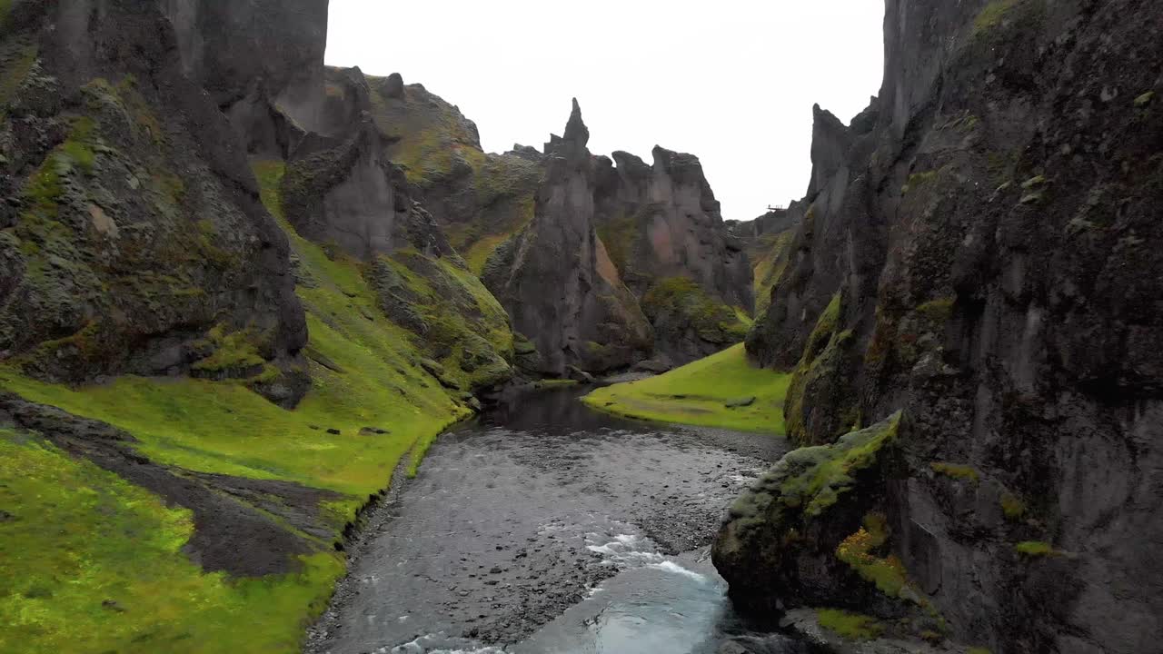 River stream flowing below sharp jagged rocks of Fjadrargljufur canyon ...