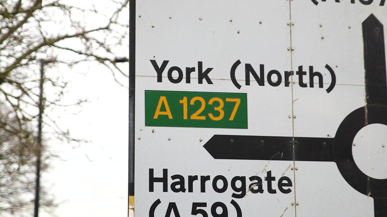 Slow pan reveals a road sign signalling to York, England