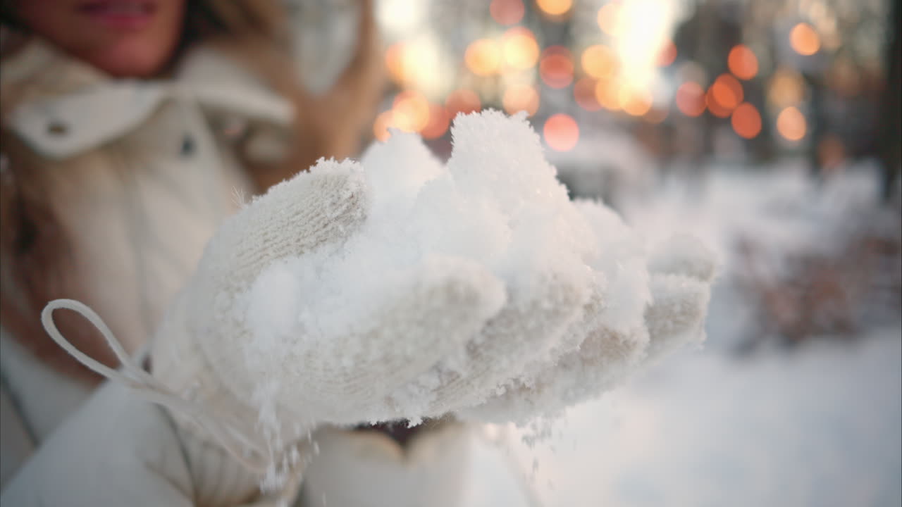 Woman having fun in winter throwing white snow in the air and smiling, slow motion