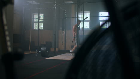 young athletic caucasian man changing putting weight lifting straps on in gym locker room before workout slow motion. ties arms to barbell with fitness straps.