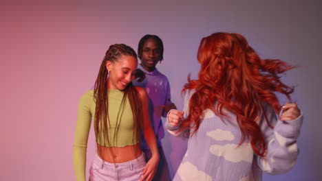 Studio-Shot-Of-Young-Gen-Z-Friends-Dancing-At-Club-Against-Pink-Background