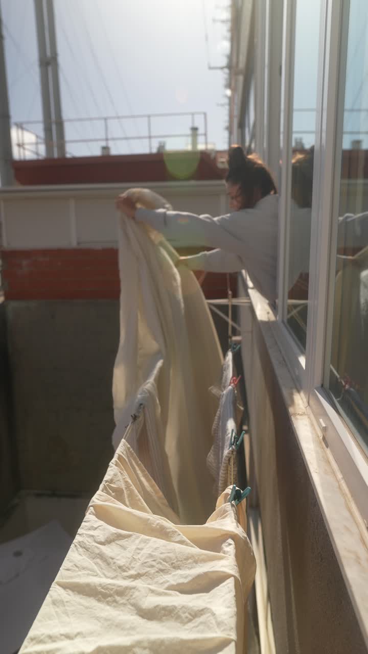 Woman Hanging Laundry on Balcony