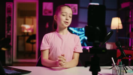 smartphone on tripod capturing footage of energetic young girl filming herself discussing topics